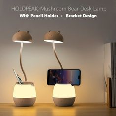 two lamps that are next to each other on a table with a cell phone in front of them