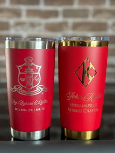 two red and gold tumblers sitting next to each other on top of a table