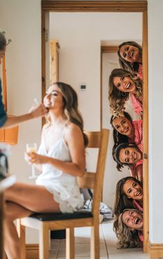 a group of women sitting on top of a wooden chair in front of a mirror