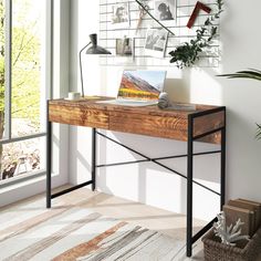 a wooden desk sitting in front of a window next to a potted green plant