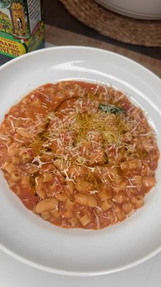 a white plate topped with beans covered in sauce next to a can of food on a table