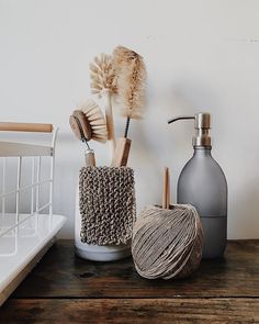 three different items are sitting on a wooden table next to a bottle, brush and soap dispenser