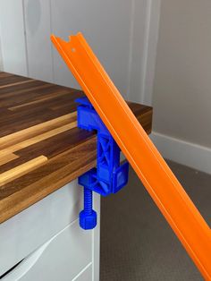 an orange and blue object on top of a wooden counter next to a white drawer