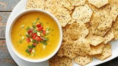 a white plate topped with tortilla chips and a bowl of soup