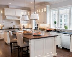 a kitchen with white cabinets and an island in the middle, surrounded by wooden flooring