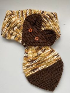 a knitted brown and white scarf with buttons on the end, sitting on top of a table