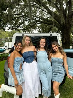 four girls posing in front of an old pick - up truck with their jeans on