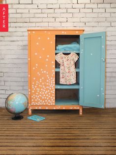 an orange and blue cabinet sitting on top of a wooden floor next to a brick wall