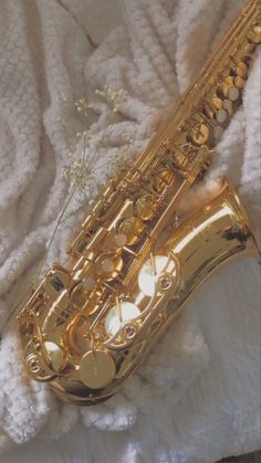 a golden saxophone sitting on top of a white blanket