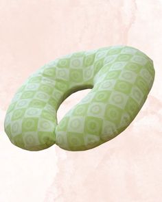 a green and white patterned pillow on a pink background