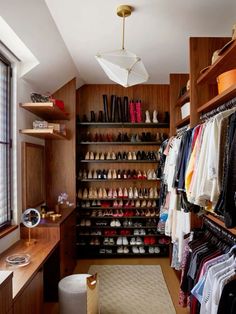 a walk in closet with lots of shoes and clothes hanging on the shelves next to it