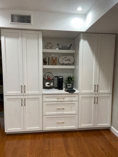 a kitchen with white cabinets and wood floors