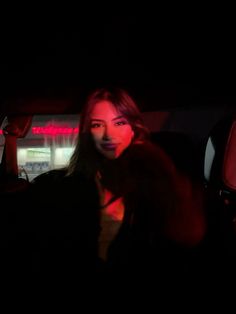 a woman sitting in the back seat of a car at night with her head turned to the side