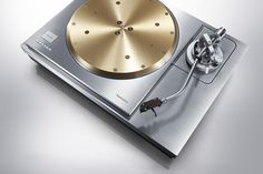 a silver and gold colored turntable sitting on top of a table