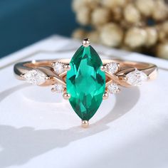 an emerald colored ring with two white diamonds on the side and one green stone in the middle