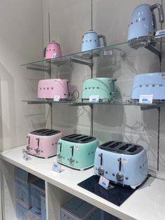 some toasters are sitting on shelves in a room with white walls and glass shelves