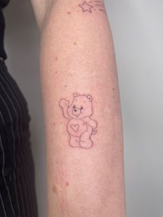 a small teddy bear tattoo on the right arm and shoulder, with stars around it