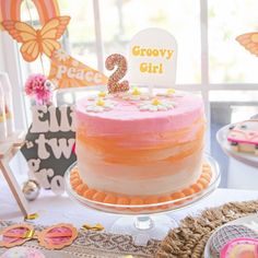 there is a pink and orange cake on the table with decorations around it, including a sign that says 2 grooy girl