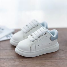 a pair of white and blue tennis shoes sitting on top of a wooden table