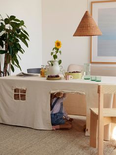 a child is hiding under a table in the living room