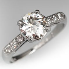 a white gold ring with diamonds on the sides and a center stone in the middle