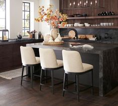 a kitchen island with four chairs and a vase on the counter in front of it