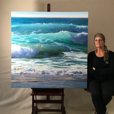 a woman sitting in front of a large painting