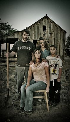 a family poses for a photo in front of an old barn