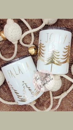 two coffee mugs sitting on top of a blanket next to christmas ornaments and decorations