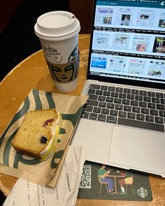 a laptop computer sitting on top of a wooden table next to a cup of coffee