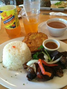 a white plate topped with rice, meat and veggies next to two drinks