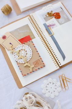 an open book with lace, paper clips and other crafting supplies on top of it