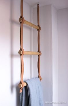 a wooden ladder hanging from the side of a white wall next to a towel rack