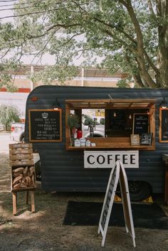 a coffee truck parked next to a tree and some signs on the side of it