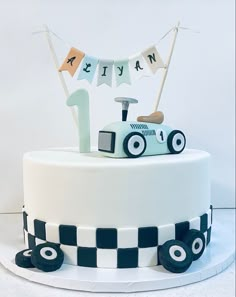 a birthday cake decorated with a race car and bunting banner for the number one