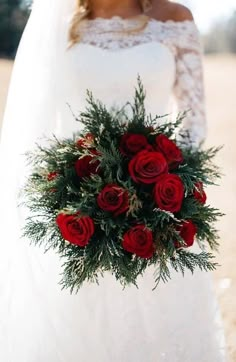 a bride holding a bouquet of red roses