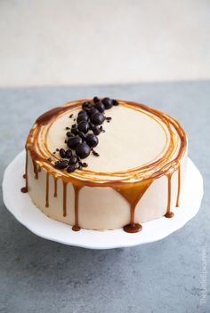 a cake with chocolate chips and caramel drizzle on top sitting on a white plate