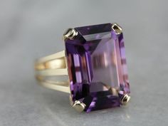 "This amethyst cocktail ring features an outstanding amethyst straight from the source, we purchased it on one of our buying trips to Brazil. The play of light is outstanding and the depth of color is exquisitely filled with flashes of violet and raspberry! A perfect piece to celebrate any occasion from anniversary to birthday and everything in between! Metal: 14K Yellow Gold Gem: Amethyst 10.00 Carats (approximately) Gem Measurements: 17.9 x 13 mm, Emerald Cut Ring Size: 6 Marks: \"14K JM\" Sta Amethyst Cocktail Ring, Emerald Cut Ring, Emerald Cut Rings, February Birthstone, February Birth Stone, The Source, Cocktail Ring, Cocktail Rings, Emerald Cut