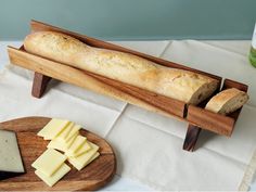 a loaf of bread sitting on top of a wooden cutting board next to sliced cheese