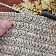 someone is crocheting the side of a piece of fabric