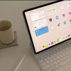 an open laptop computer sitting on top of a white desk next to a cup of coffee