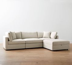 a white sectional couch with pillows on top of it in an empty living room area