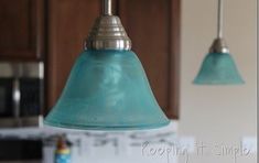 two blue glass lights hanging from a kitchen ceiling