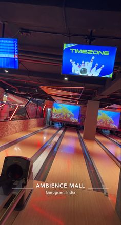 the bowling alley is full of bowling pins and video screens with neon lights on them