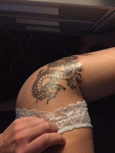 a woman's arm with tattoos on it and a lace garter around her waist