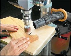 a person working on a piece of wood with a machine in front of him and another hand holding a tool