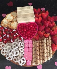 valentine's day snack board with pretzels, crackers, strawberries, raspberries and heart shaped cookies