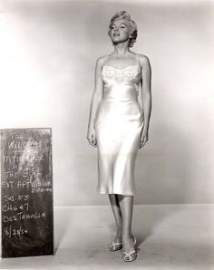 an old photo of a woman standing next to a chalkboard with writing on it