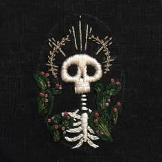 a black sweater with a white skeleton and holly wreath on the front, embroidered onto it