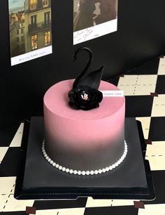 a pink cake with a black swan decoration on top